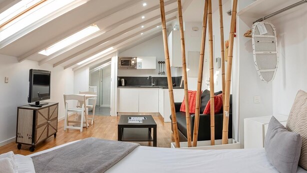Un loft moderno con techos altos, tragaluces, una cocina, sala de estar y un dormitorio.