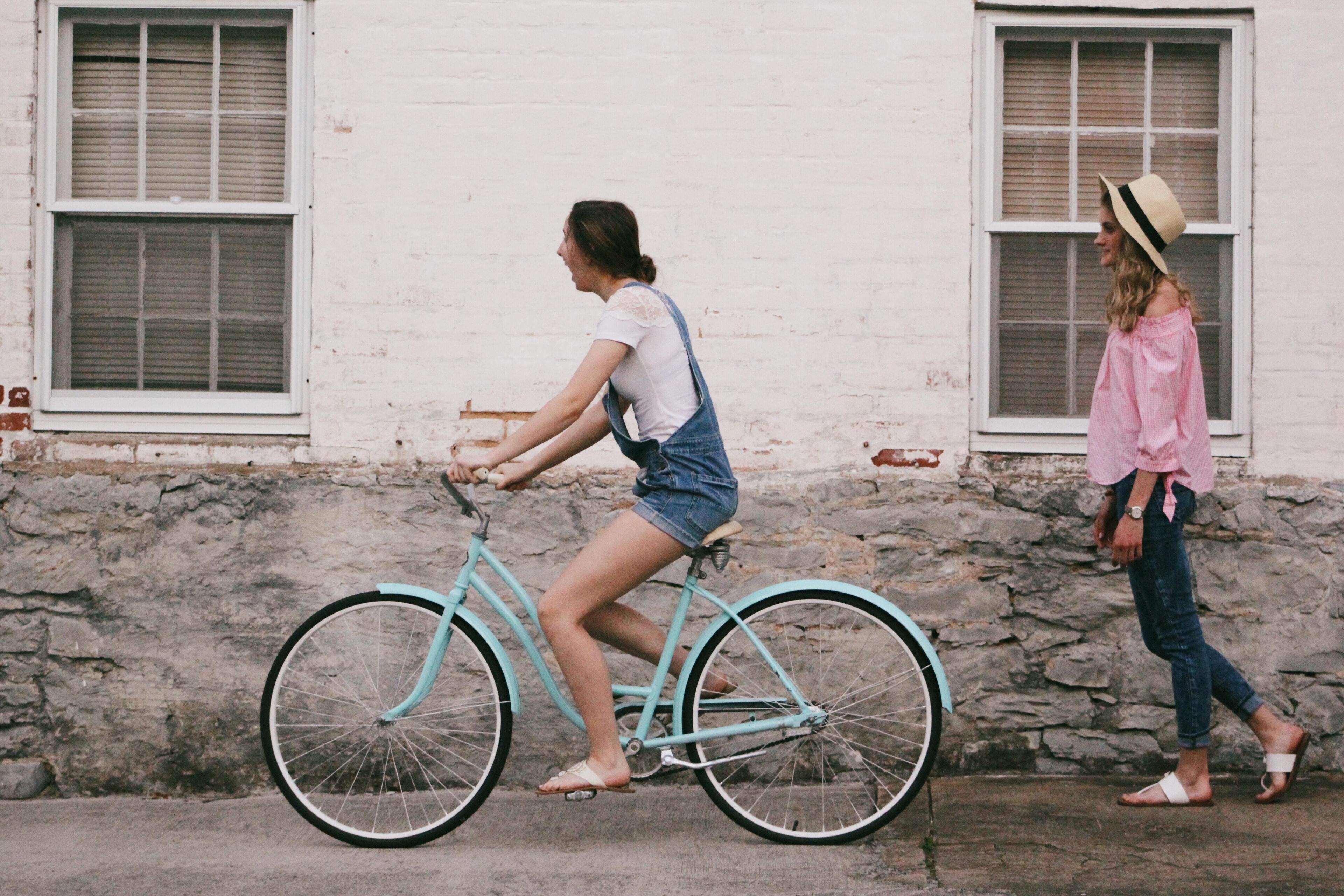 Une personne à vélo, de couleur turquoise, circule sur un chemin pavé.