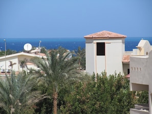 A coastal building with a tiled roof, a satellite dish, and a view of the sea.