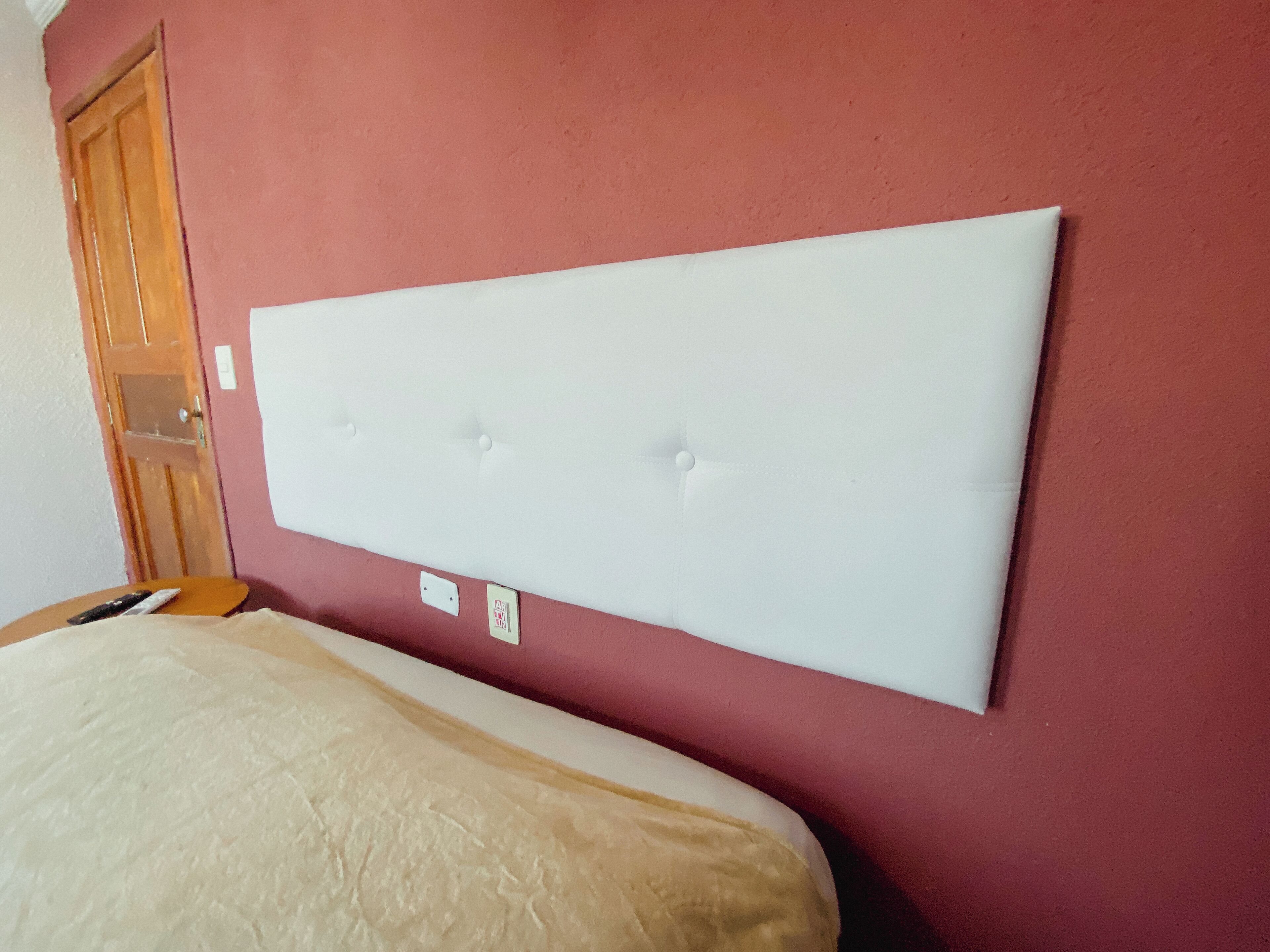 Una habitación con una cama grande, una puerta de madera y una pared roja.