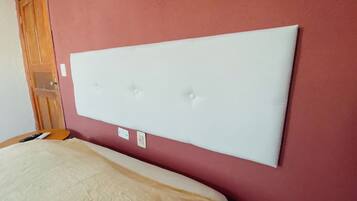 Una habitación con una cama grande, una puerta de madera y una pared roja.