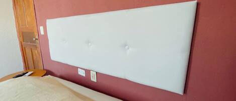 Una habitación con una cama grande, una puerta de madera y una pared roja.