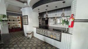 A kitchen with white tiled walls, a black countertop, and hanging pendant lights. - Hotel 5 Sóis (Olinda)