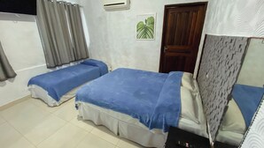 A room with two beds, a TV, an air conditioner, a door, and a plant. - Hotel 5 Sóis (Olinda)