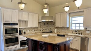 A spacious kitchen with white cabinetry, a large island, and built-in appliances. - Casa Blanca Main House, Riverview, 10 Beds, Group-Friendly (Kerr County)