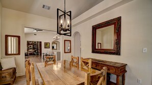 A spacious dining area with a wooden table and chairs, a chandelier, and a large ornate mirror on the wall. - Casa Blanca Main House, Riverview, 10 Beds, Group-Friendly (Kerr County)