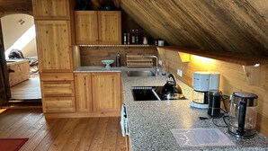 A cozy kitchen with wooden cabinets, granite countertops, and a built-in stove. - Charming guest apartment in an old farmhouse in a secluded alpine location (Sonnberg)