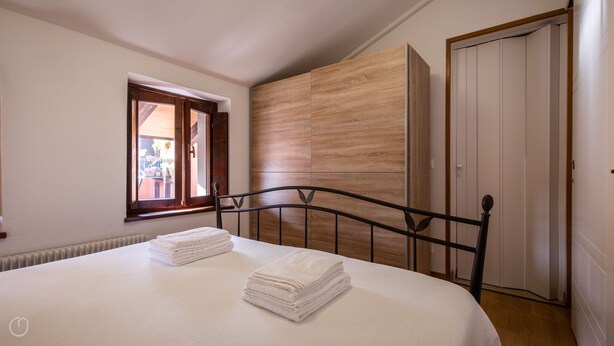 Una camera da letto con un letto, una finestra, un armadio e un termosifone.