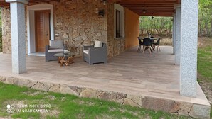 Un espacio de estar al aire libre cubierto con paredes de piedra y vigas de madera, que incluye dos sofás y una mesa.