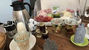 A kitchen counter with various food items, including jars of pickles, a coffee maker, and a plastic container with sliced meats and vegetables. - Weingut Manuel Sauer (Nordheim a. Main)