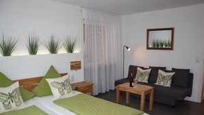 A bedroom with a bed, a sofa, a small table, and a lamp. - Weingut Manuel Sauer (Nordheim a. Main)
