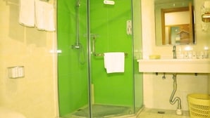 A bathroom with a glass-enclosed shower, a sink with a mirror above it, and a towel rack with towels. - Greentree Inn Beijing Fangshan District Jingzhou Road Magezhuang Subway Station Express Hotel (Fangshan)