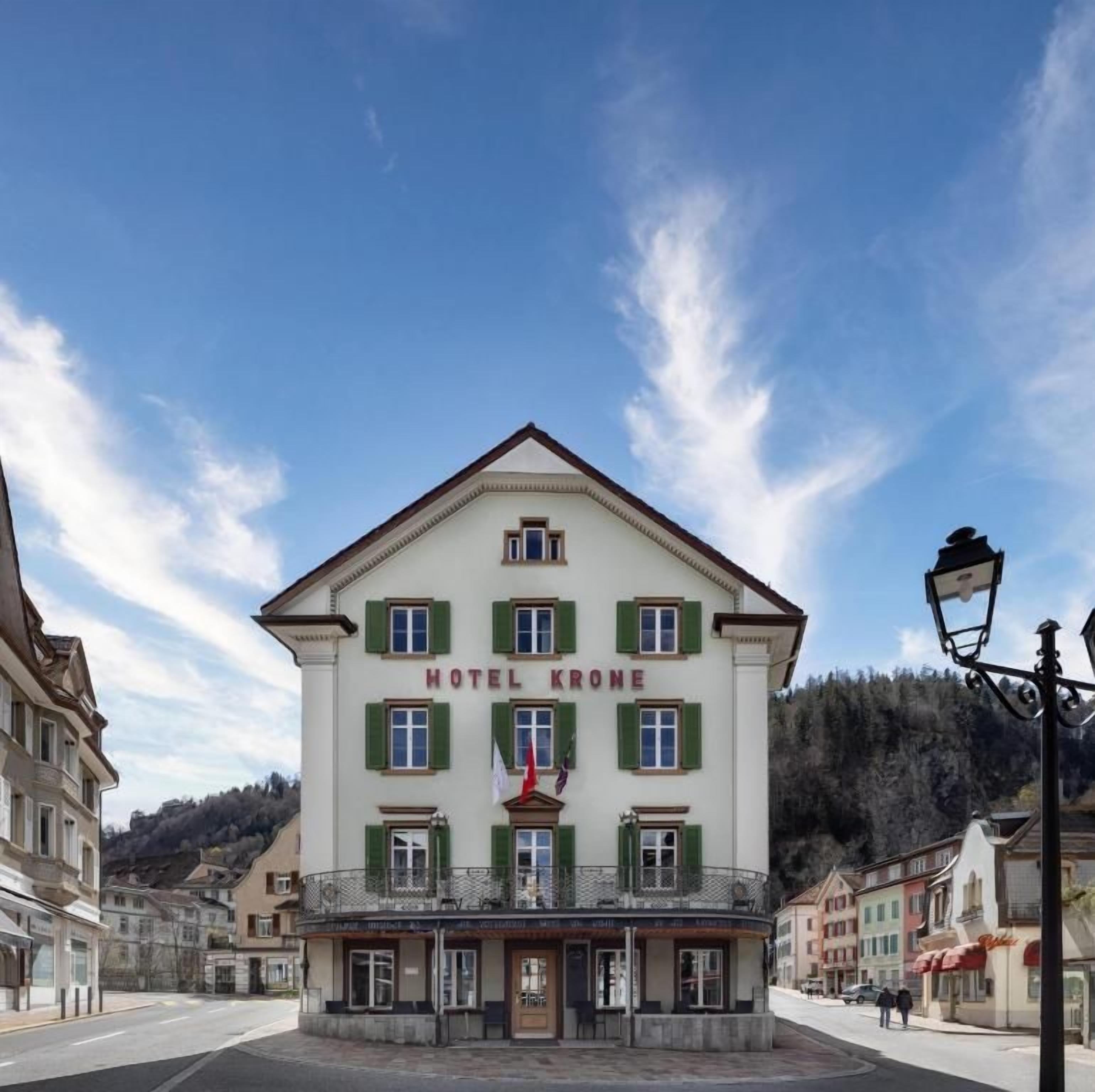 Un edificio de hotel con un balcón, una bandera y un cartel que dice 'HOTEL KRONE'.