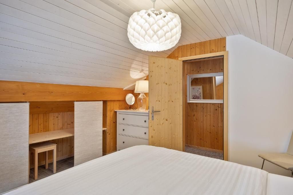 A bedroom with a bed, a dresser, a chair, and a wooden wardrobe.