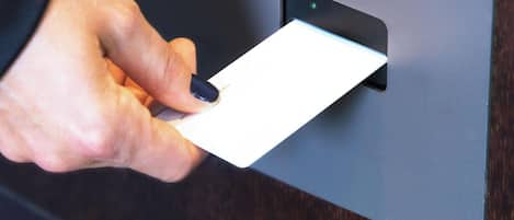 Una mano sosteniendo una tarjeta sobre una superficie negra, posiblemente un lector de tarjetas.