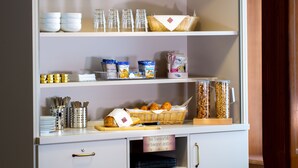 Una cocina con estantes llenos de frascos, bolsas de aperitivos y una cesta de pan.