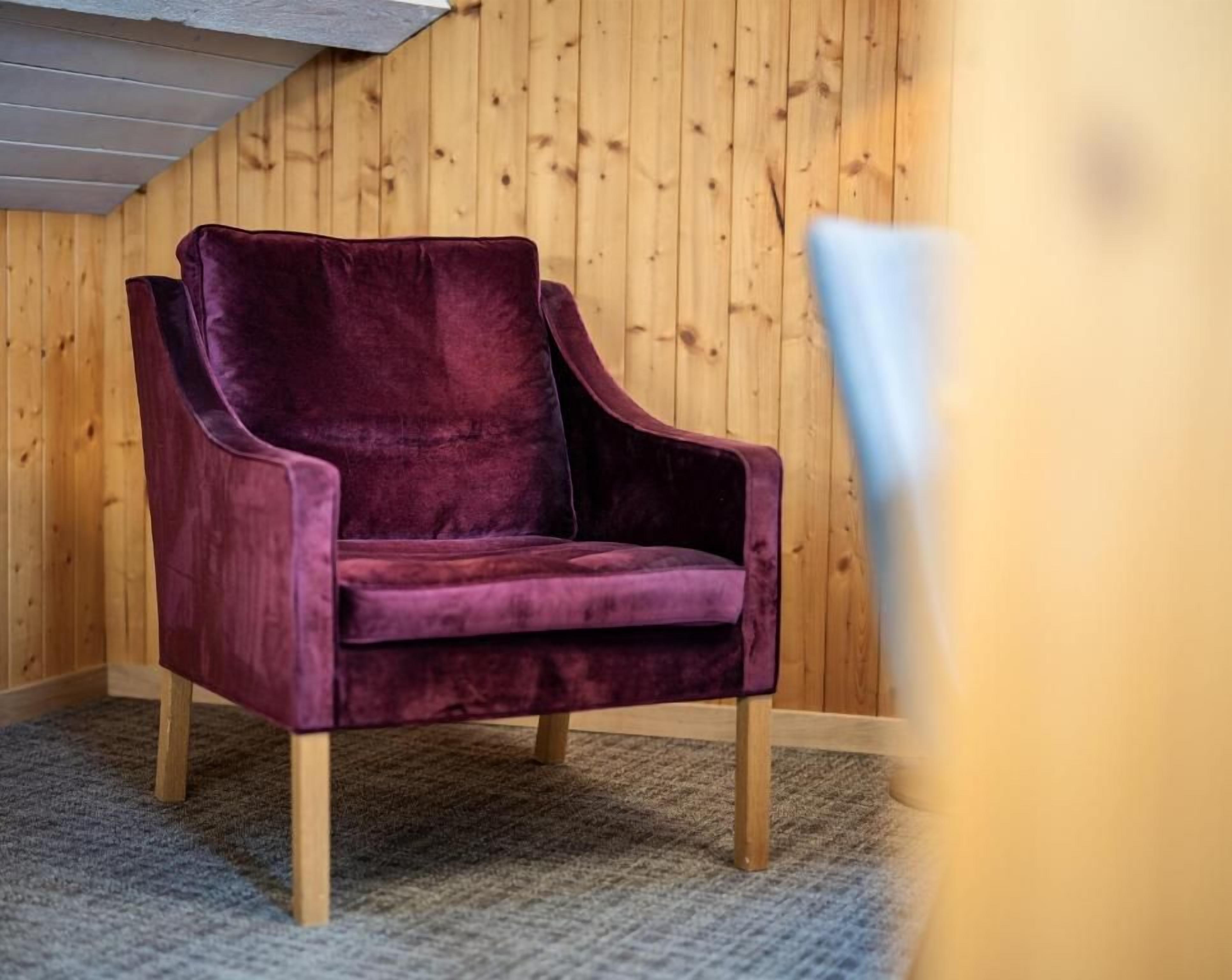 A single purple armchair in a room with wooden walls and a carpeted floor.