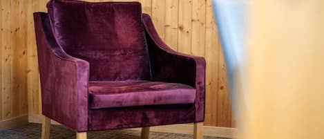 A single purple armchair in a room with wooden walls and a carpeted floor.