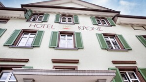 Un edificio con el letrero "HOTEL KRONE" y contraventanas verdes.
