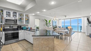 Een moderne keuken met een centraal eiland, een eethoek met uitzicht en een balkon dat uitkijkt op de oceaan.