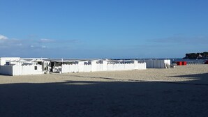 Une plage avec des cabanes de plage blanches et un ciel dégagé.