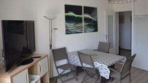 Un espace repas comprenant une table, des chaises, un téléviseur et des œuvres d’art accrochées au mur.