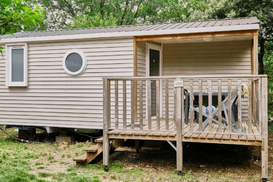 A mobile home with a wooden deck and a small porch area.