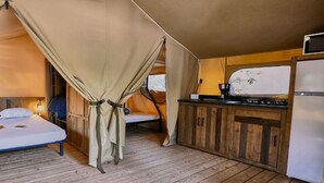 A tented accommodation with a bed, a small kitchenette, and a window. - Domaine des Chênes Blancs - Camping (Saint-Saturnin-les-Apt)