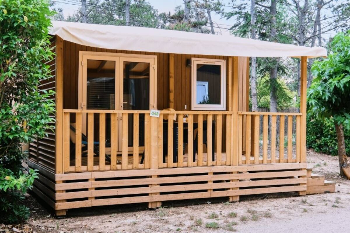 A wooden cabin with a covered porch, windows, and a small door.