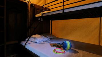 A bunk bed room with a single bed on the lower bunk, a light fixture above, and a ball and rings on the bed.