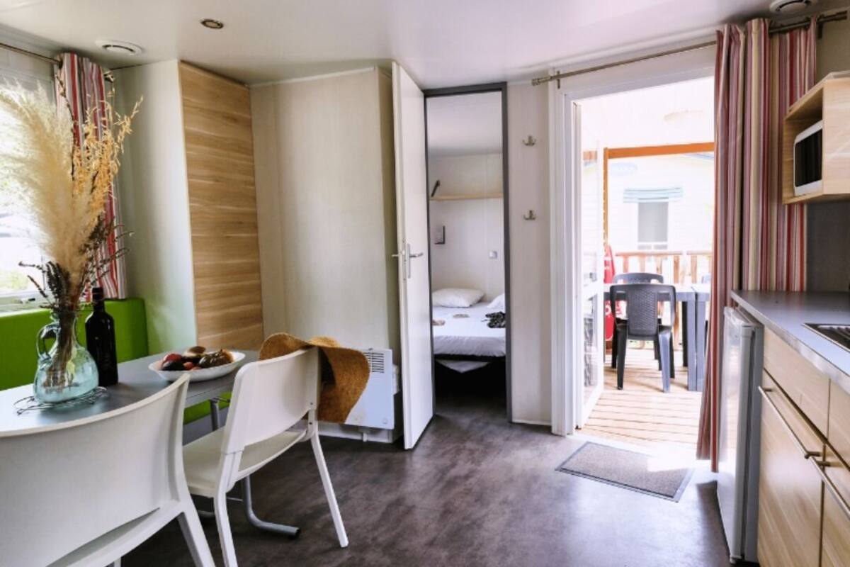 A compact hotel room with a kitchenette, a dining area, and a bed.