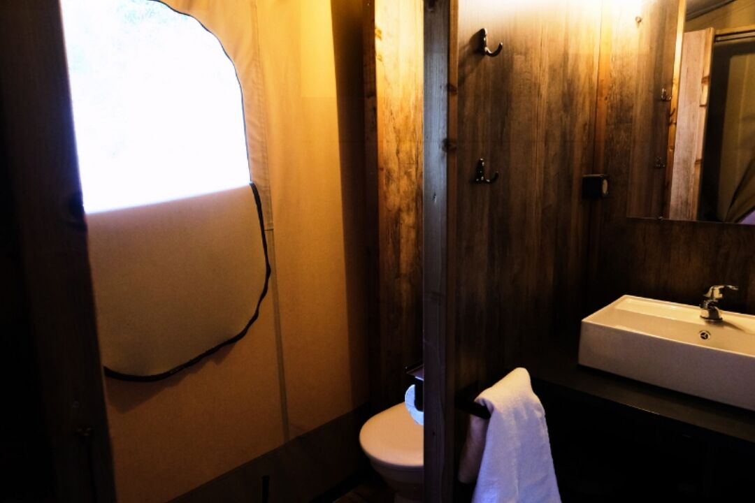 A bathroom with a wooden door, a white sink, and a toilet.