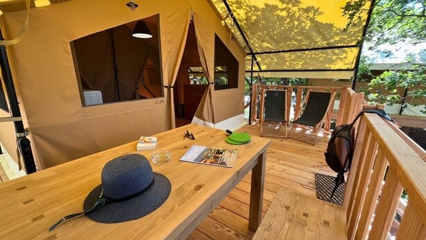 A wooden deck with a table, a hat, and a magazine. - Domaine des Chênes Blancs - Camping (Saint-Saturnin-les-Apt)
