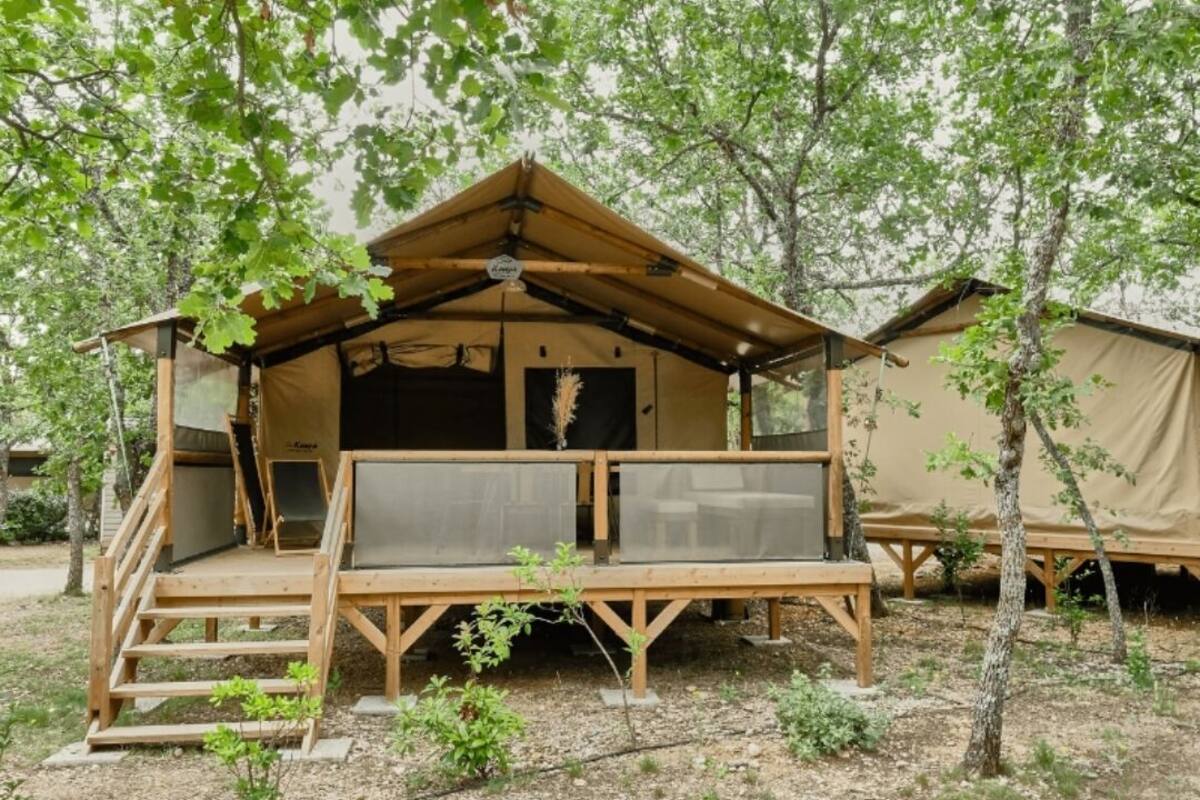 A wooden tent with a balcony and a staircase leading up to it.