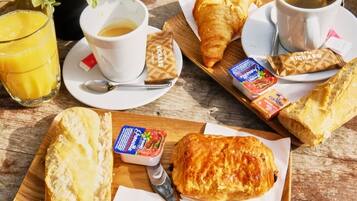 A breakfast setting with croissants, coffee, and juice on a wooden table.