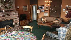 A cozy living room with a fireplace, a sofa, a coffee table, and a patterned rug. - Priest Lake BEACHFRONT w 2 slip Dock (Priest Lake Idaho)