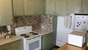 A kitchen with green cabinets, a white stove, and a refrigerator. - Priest Lake BEACHFRONT w 2 slip Dock (Priest Lake Idaho)