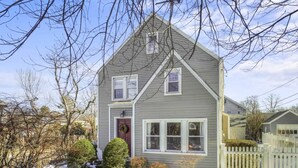 A two-story house with a gabled roof, a front porch, and a picket fence. - Belltown Retreat - Shopping, Dining, Pet Friendly (Stamford)