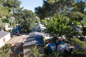 Un camping con varias caravanas y tiendas de campaña, rodeado de árboles y vegetación.