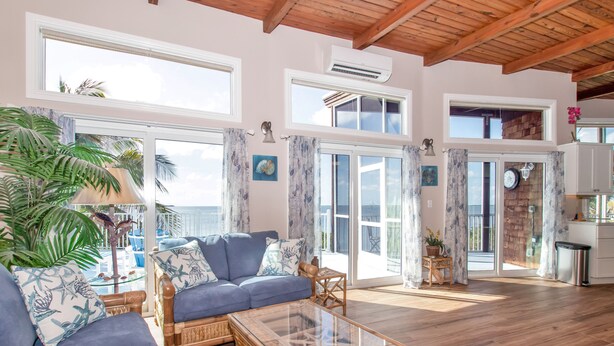 A spacious living area with a blue sofa, glass coffee table, and large windows.
