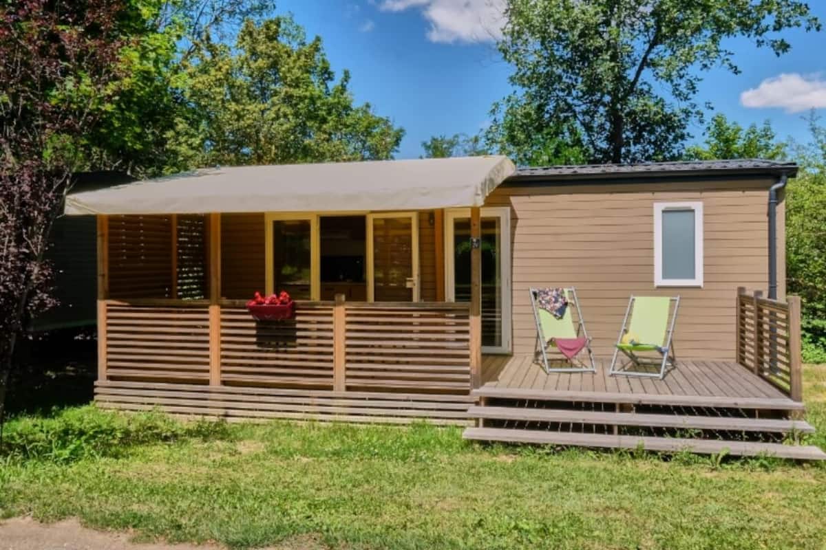Eine kleine Holzhütte mit Veranda und zwei Stühlen.