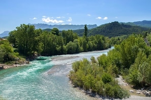A river flowing through a forested area with mountains in the background. - Domaine du Couriou (Recoubeau-Jansac)