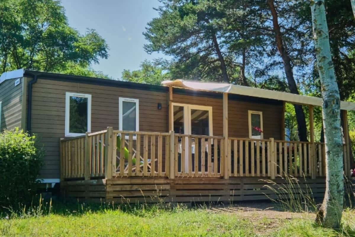 Ein Holz-Wohnmobil mit einer Veranda und einer überdachten Terrasse.