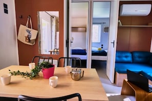 A compact living space with a dining table, chairs, a sofa, and a bed. - Domaine du Couriou (Recoubeau-Jansac)