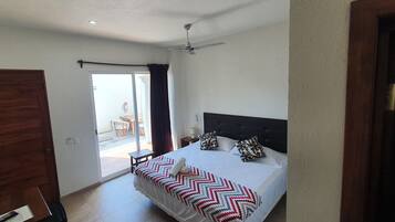 Une chambre d’hôtel avec un lit, un ventilateur de plafond, une porte et une vue sur l’extérieur.