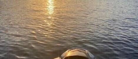 A motorcycle on a body of water with the sun setting in the background.