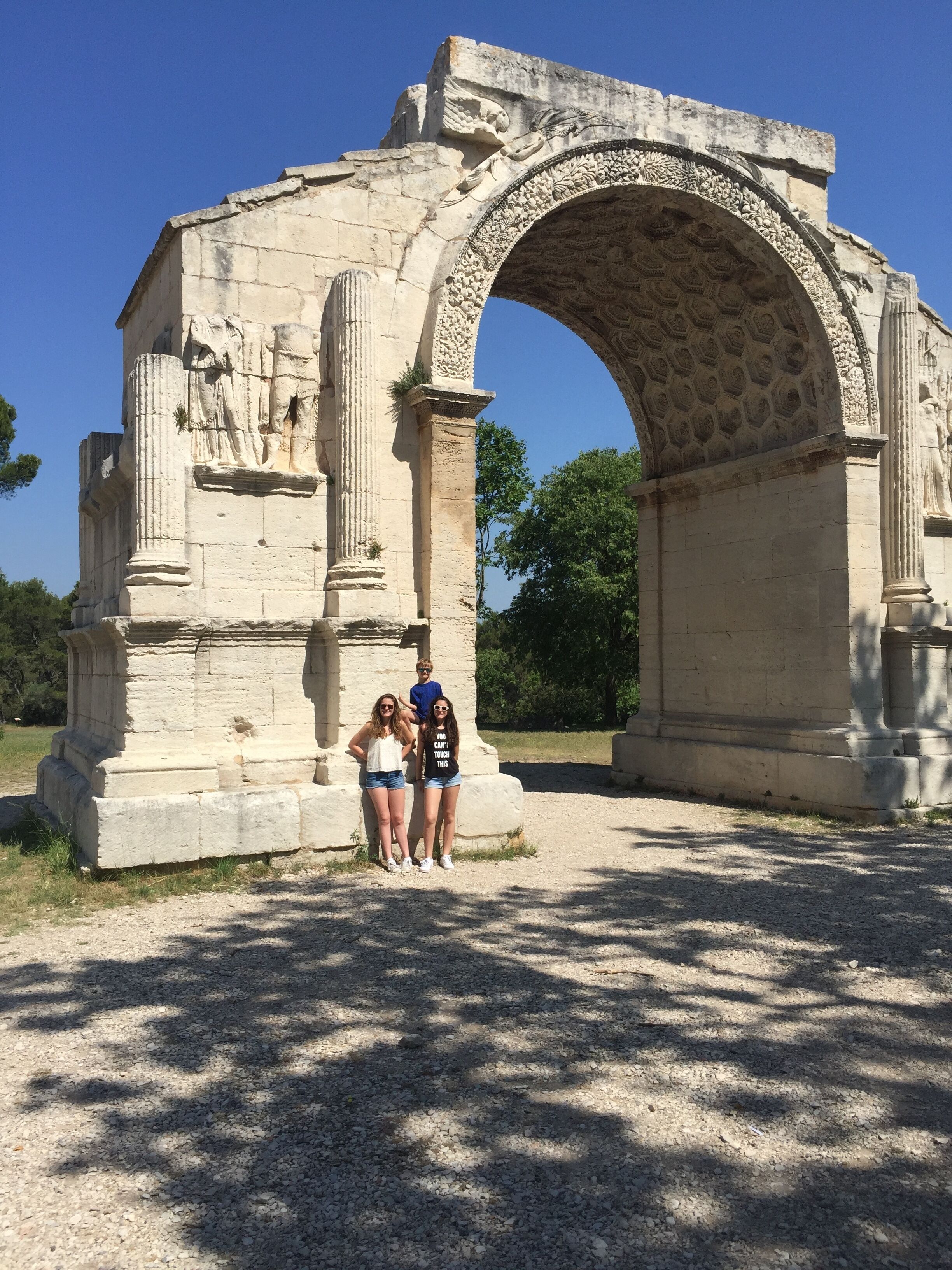 An ancient stone archway with intricate carvings and two people standing in front of it.