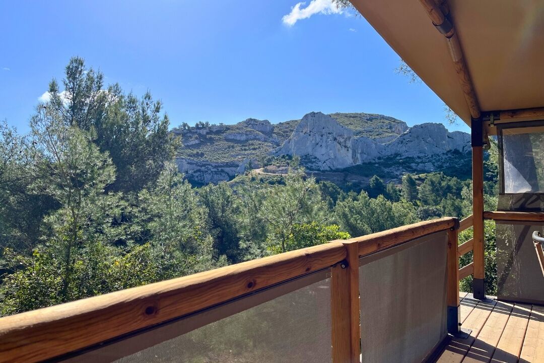 A wooden balcony with a view of a mountainous landscape and dense forest.