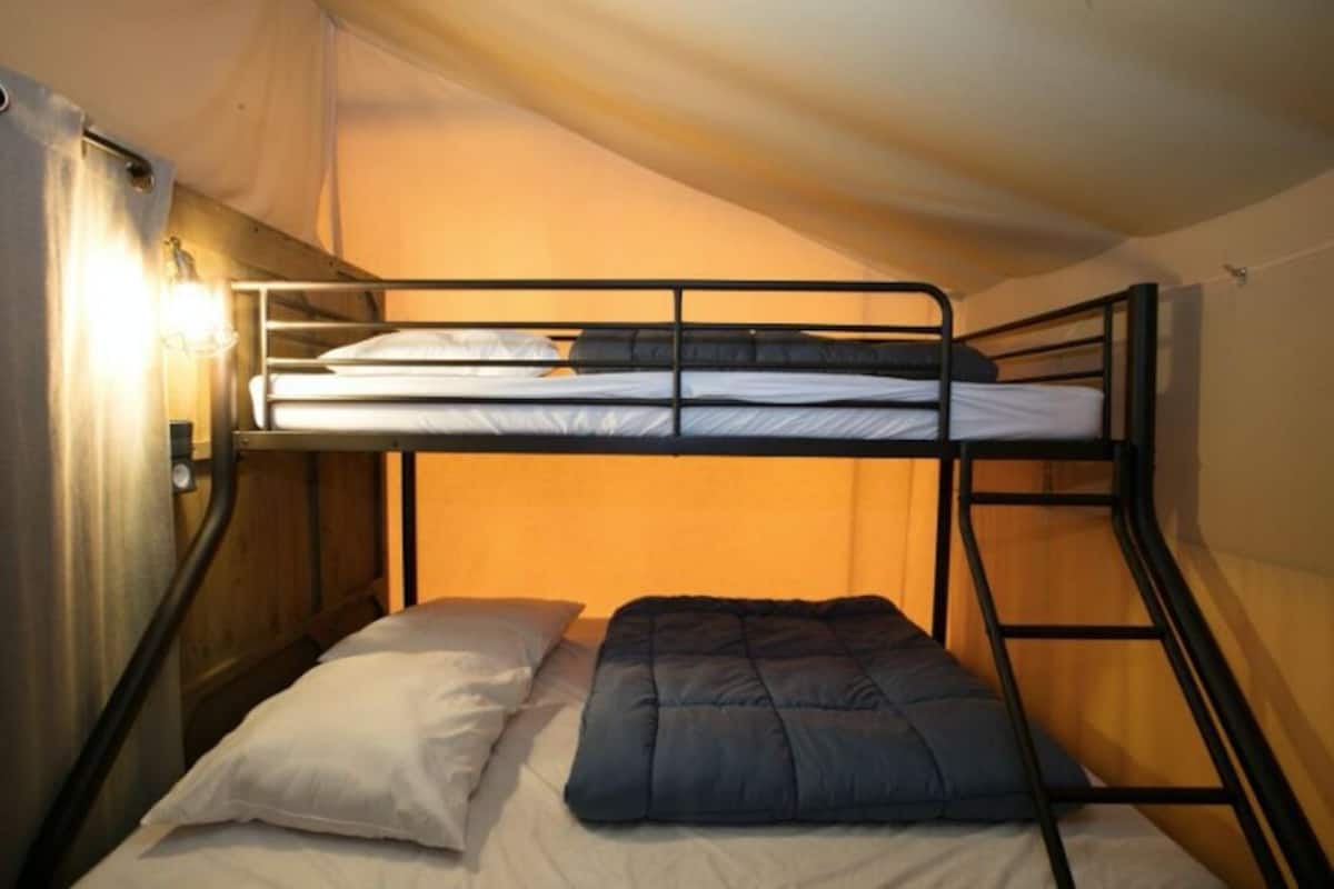 A bunk bed with a headboard and a bedside table with a lamp.