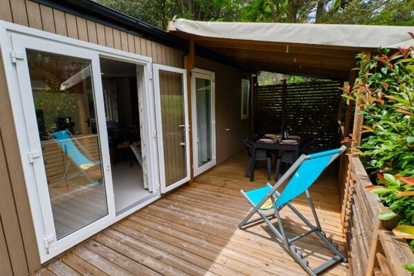 A wooden deck with a covered patio area, a sliding glass door, and a blue folding chair.